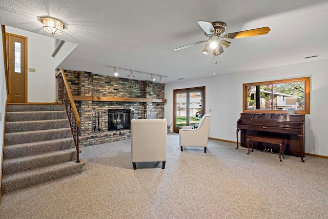 carpeted living area with ceiling fan, stairs, baseboards, track lighting, and a textured ceiling