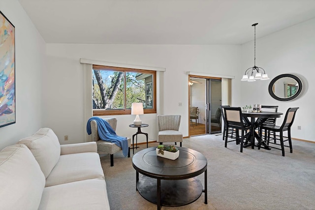 carpeted living room with lofted ceiling, a chandelier, and baseboards