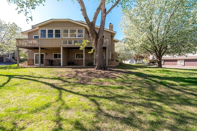 rear view of house with a chimney, a deck, a lawn, and cooling unit