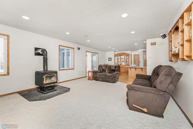 3358 70th Ave N, Moorhead, MN 56560 - living area featuring light carpet, recessed lighting, a textured ceiling, a wood stove, and baseboards