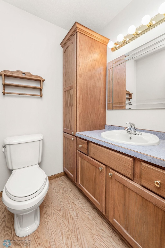 3358 70th Ave N, Moorhead, MN 56560 - half bathroom featuring vanity, toilet, and wood finished floors