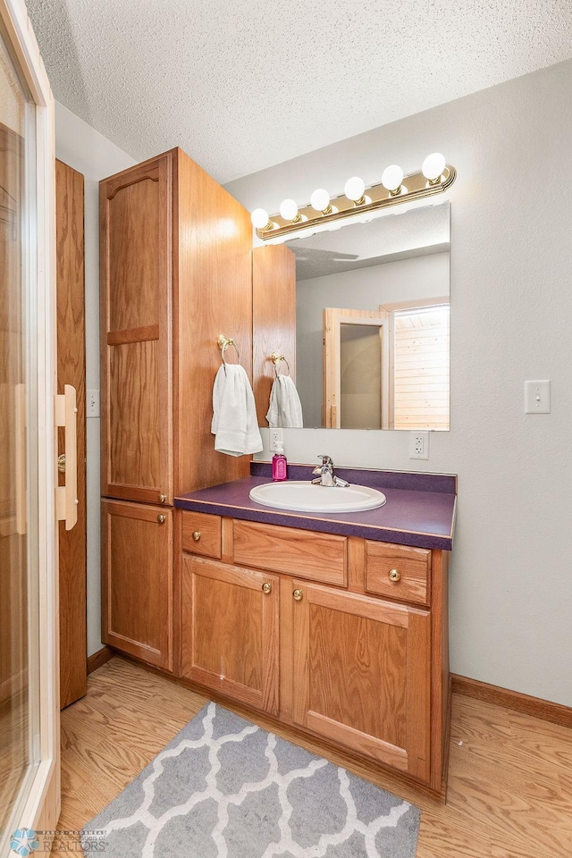 3358 70th Ave N, Moorhead, MN 56560 - bathroom with wood finished floors, vanity, baseboards, and a textured ceiling