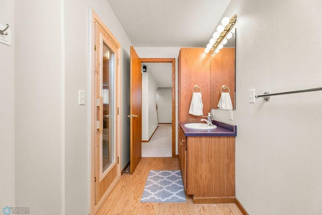 3358 70th Ave N, Moorhead, MN 56560 - bathroom with vanity, wood finished floors, a textured ceiling, and baseboards