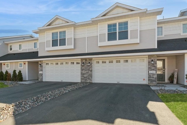 view of property featuring a garage, driveway, stone siding, and board and batten siding