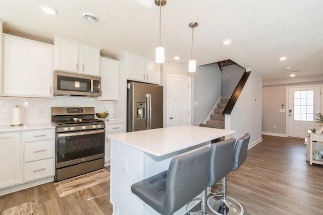 kitchen featuring a center island, tasteful backsplash, light wood finished floors, baseboards, and appliances with stainless steel finishes