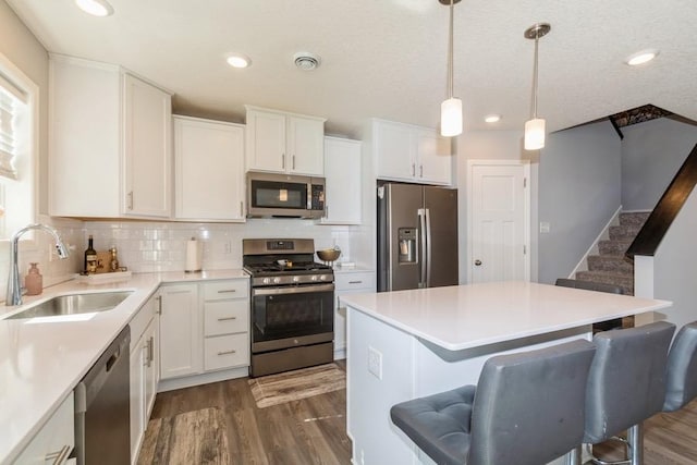 kitchen featuring stainless steel appliances, a breakfast bar, dark wood-style floors, and a sink