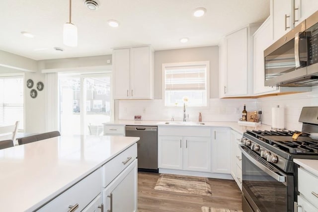 kitchen with decorative backsplash, light wood finished floors, stainless steel appliances, and a sink