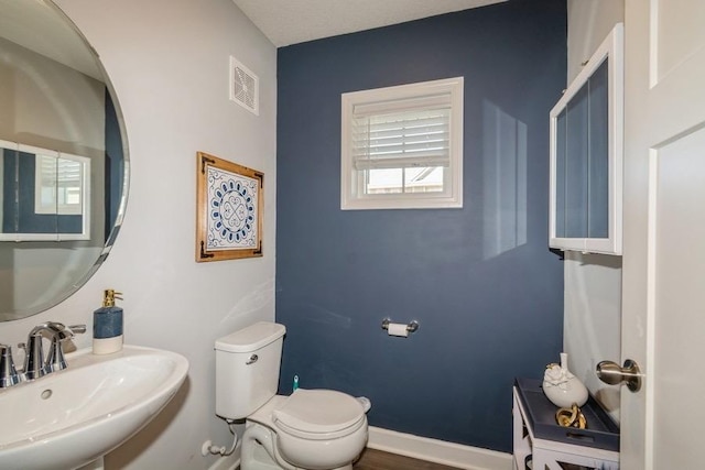 bathroom with visible vents, toilet, and a sink