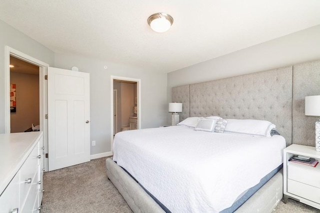 bedroom with ensuite bath and light carpet