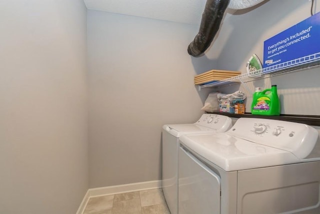 washroom with baseboards, washer and clothes dryer, and laundry area