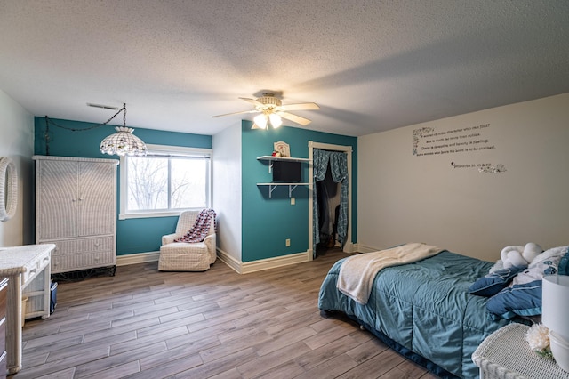 34506 Pleasant Point Dr, Homer Twp, MN 55987 - bedroom featuring a textured ceiling, wood finished floors, a closet, baseboards, and ceiling fan