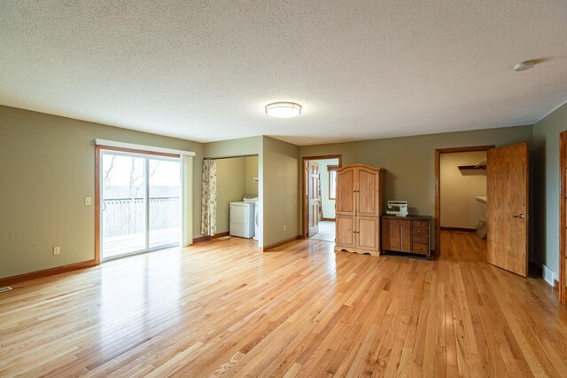 34506 Pleasant Point Dr, Homer Twp, MN 55987 - unfurnished living room with washer / clothes dryer, light wood-type flooring, a textured ceiling, and baseboards