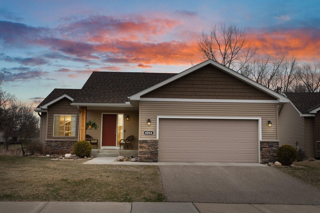 6044 Iris Ln, Rockford, MN 55373 - craftsman-style house featuring a shingled roof, an attached garage, stone siding, aphalt driveway, and a front lawn