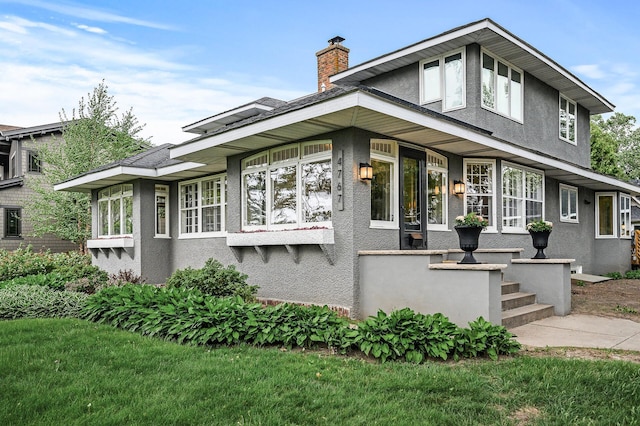 4767 Lake Ave, White Bear Lake, MN 55110 - view of front of house with stucco siding, a chimney, and a front lawn