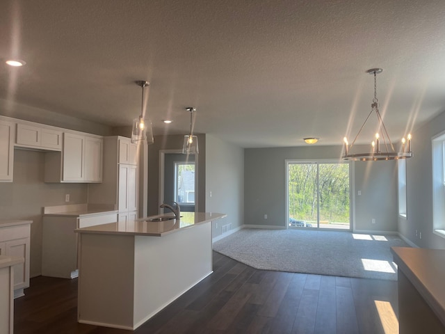 1591 76th St W, Inver Grove Heights, MN 55077 - kitchen with white cabinetry, a textured ceiling, a chandelier, an island with sink, and dark wood-type flooring