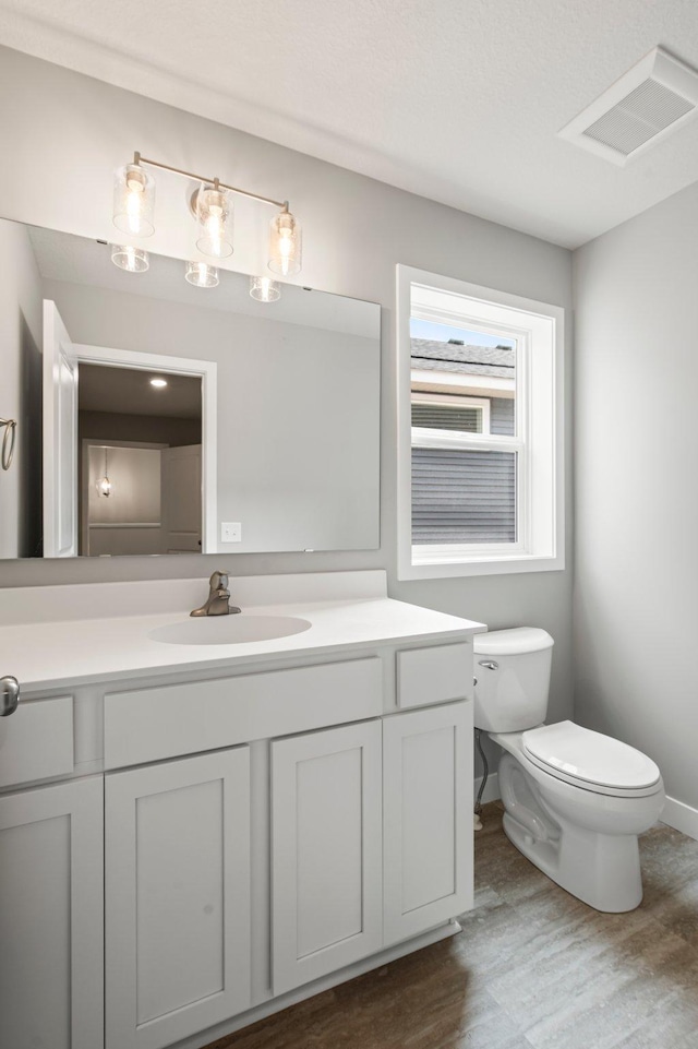 1591 76th St W, Inver Grove Heights, MN 55077 - half bathroom featuring toilet, wood finished floors, vanity, and baseboards