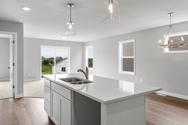 1591 76th St W, Inver Grove Heights, MN 55077 - kitchen with a sink, light wood finished floors, baseboards, light countertops, and a chandelier