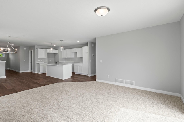 1591 76th St W, Inver Grove Heights, MN 55077 - unfurnished living room with dark colored carpet, baseboards, a chandelier, and a sink