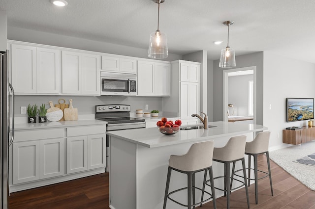 1591 76th St W, Inver Grove Heights, MN 55077 - kitchen featuring appliances with stainless steel finishes, dark wood-style floors, white cabinetry, a center island with sink, and recessed lighting