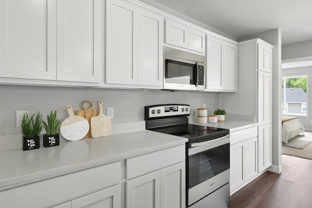 1591 76th St W, Inver Grove Heights, MN 55077 - kitchen with appliances with stainless steel finishes, dark wood finished floors, white cabinetry, light countertops, and a textured ceiling