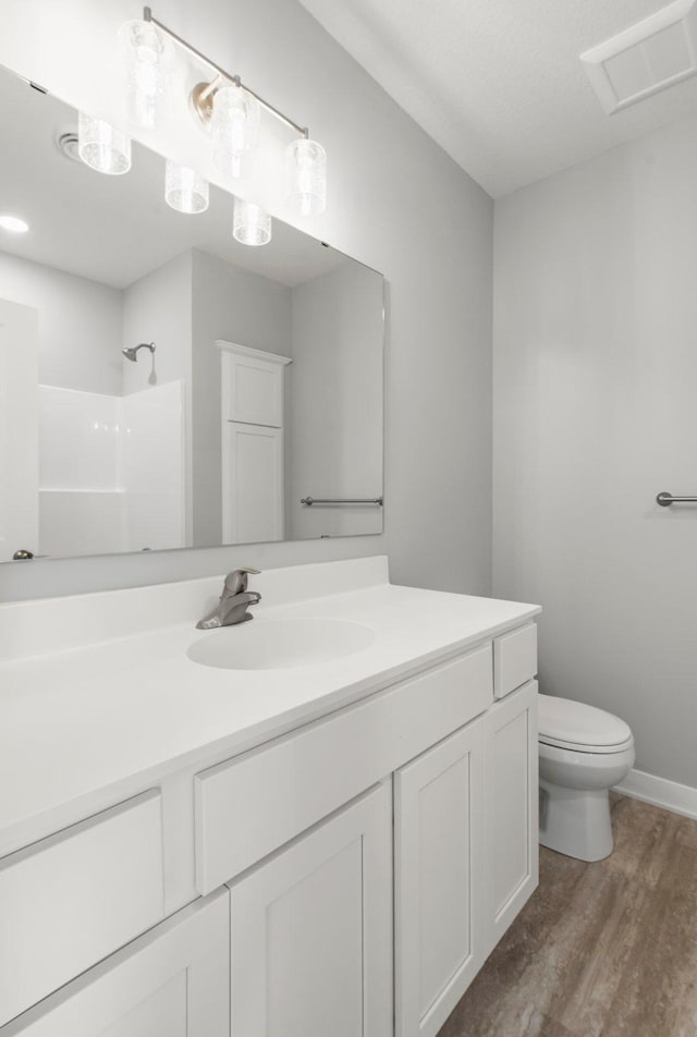 1591 76th St W, Inver Grove Heights, MN 55077 - bathroom featuring toilet, vanity, wood finished floors, a shower, and baseboards