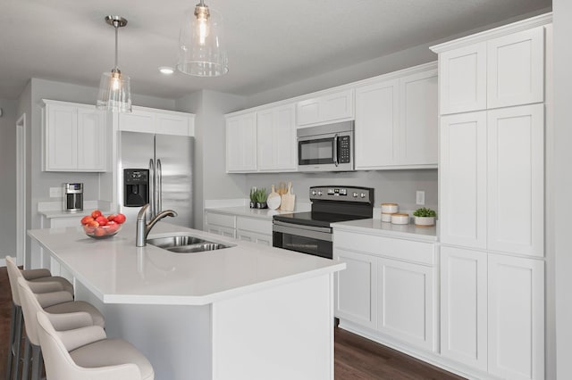 1591 76th St W, Inver Grove Heights, MN 55077 - kitchen featuring appliances with stainless steel finishes, a sink, a center island with sink, a kitchen breakfast bar, and white cabinetry