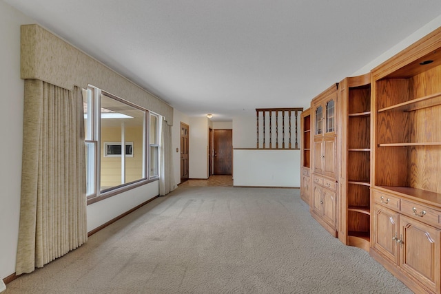 unfurnished living room with baseboards and light carpet