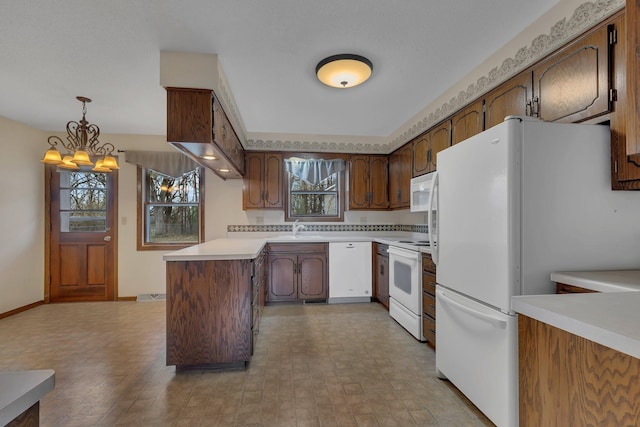 kitchen featuring a sink, white appliances, light countertops, a peninsula, and pendant lighting