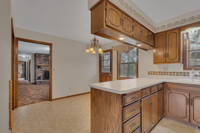 kitchen with brown cabinets, a peninsula, a sink, and light countertops