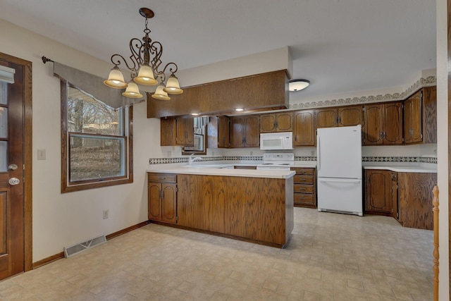 kitchen featuring visible vents, an inviting chandelier, a peninsula, white appliances, and light countertops