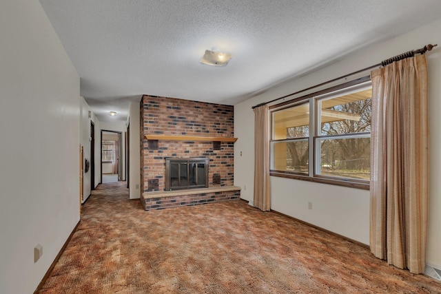 unfurnished living room featuring carpet floors, a textured ceiling, a brick fireplace, and baseboards