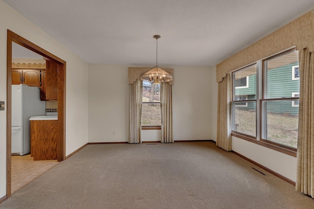 unfurnished dining area featuring baseboards, a notable chandelier, light carpet, and visible vents