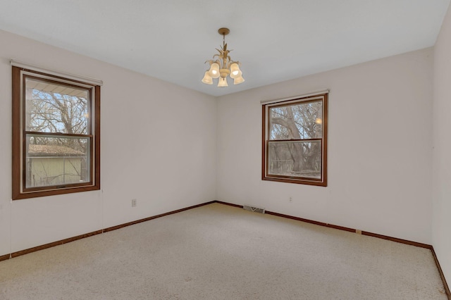 unfurnished room with a chandelier, visible vents, a wealth of natural light, and carpet