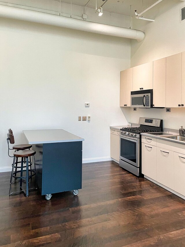 700 Washington Ave N Unit 617, Minneapolis, MN 55401 - kitchen with a breakfast bar, baseboards, a sink, dark wood finished floors, and appliances with stainless steel finishes
