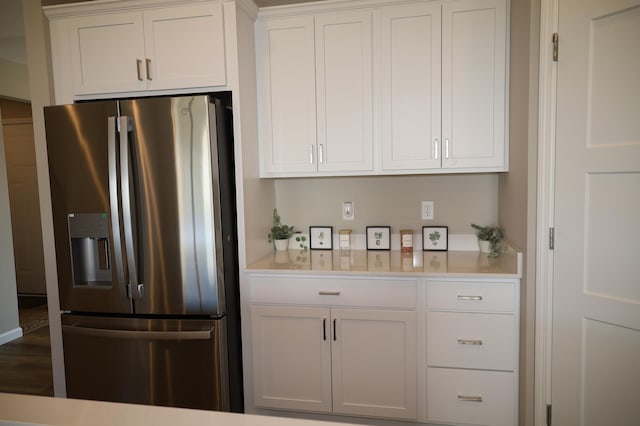 kitchen featuring light countertops, stainless steel refrigerator with ice dispenser, and white cabinetry