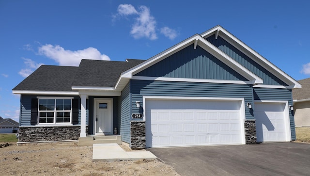 craftsman house featuring a garage, driveway, and stone siding