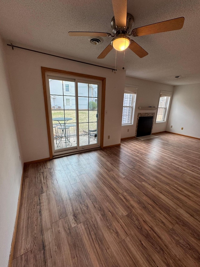 unfurnished living room featuring wood finished floors, a ceiling fan, a textured ceiling, visible vents, and baseboards