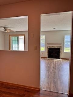 interior space featuring a fireplace, baseboards, a ceiling fan, and wood finished floors