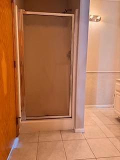 full bathroom featuring baseboards, tile patterned flooring, and a shower stall