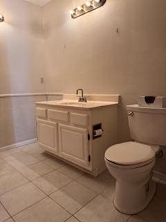 bathroom featuring toilet, baseboards, tile patterned floors, and vanity