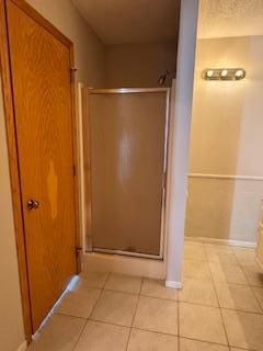 full bathroom with tile patterned flooring, baseboards, and a shower stall