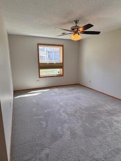carpeted spare room featuring a textured ceiling, baseboards, and a ceiling fan