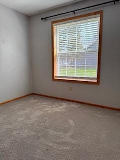 carpeted empty room featuring baseboards