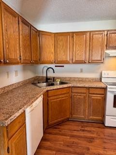 kitchen with brown cabinets, white appliances, and a sink