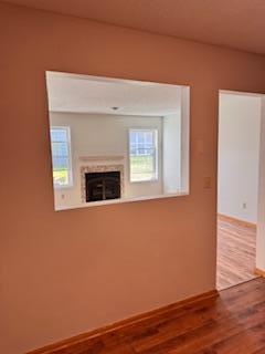 unfurnished living room featuring wood finished floors, baseboards, and a fireplace