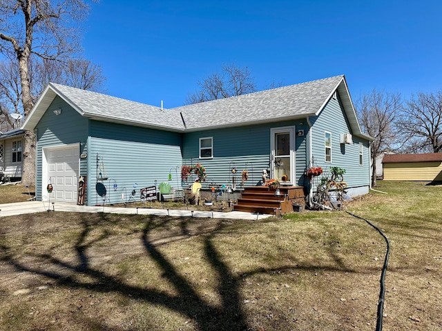 rear view of property featuring a garage, a shingled roof, and a lawn