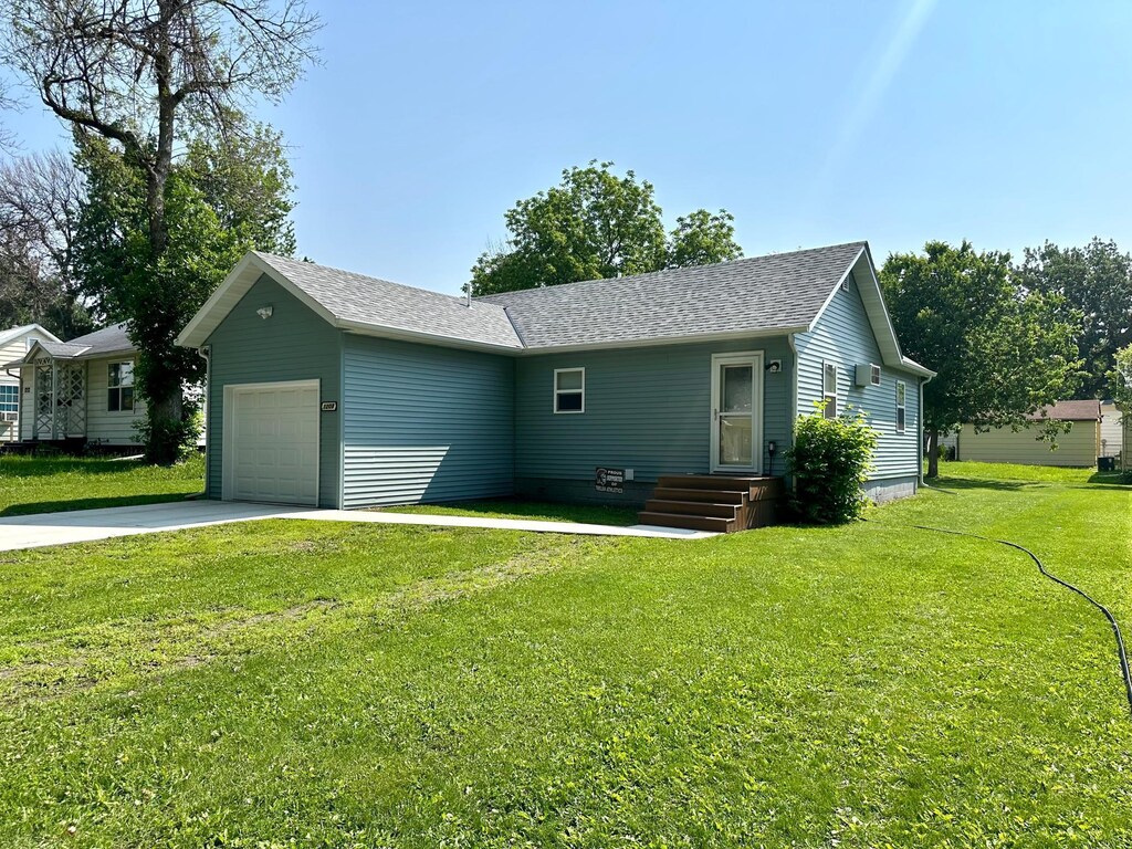 1208 Apel Ave, Worthington, MN 56187 - view of front facade featuring a garage, a front lawn, driveway, and a shingled roof