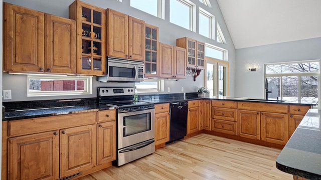 kitchen with a sink, brown cabinetry, light wood-style flooring, and appliances with stainless steel finishes