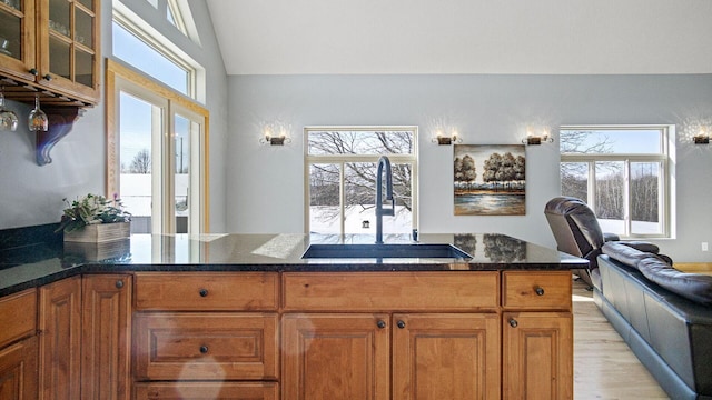 kitchen featuring a sink, a wealth of natural light, dark stone counters, and brown cabinets