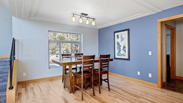 dining room featuring track lighting, baseboards, and light wood-type flooring